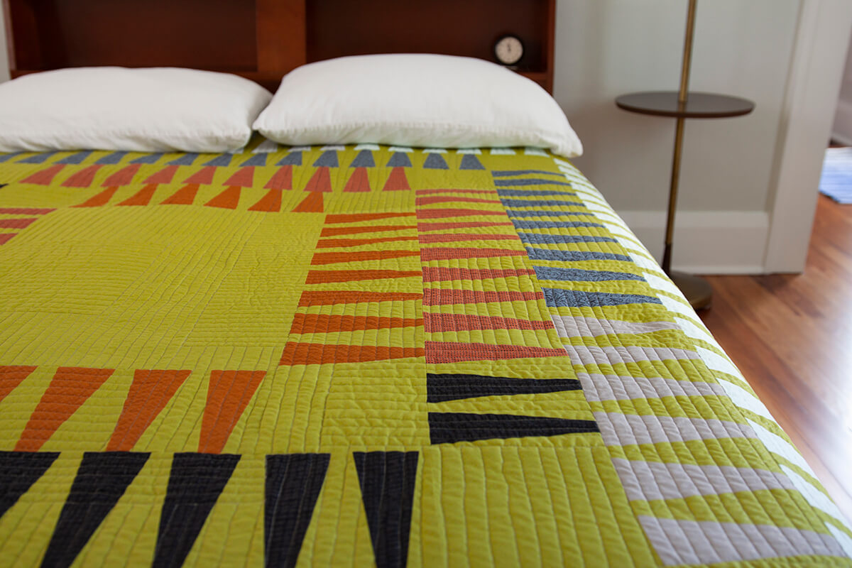 frond quilt on a bed by carolyn friedlander
